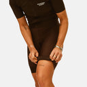 Ciclista ajustando los bibs de dama Essential de Pas Normal Studios en color marrón oscuro, disponibles en Velo Store Mx.