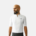 Ciclista con jersey blanco Pas Normal Studios Essential de corte relajado, ideal para rutas largas y clima cálido.