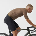 Ciclista con jersey Pas Normal Studios Solitude Mesh color marrón sobre bicicleta de ruta en posición aerodinámica