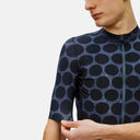 Ciclista vistiendo el jersey Pas Normal Studios Essential en color Dot Dark Navy con patrón de puntos y cremallera YKK.