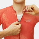 Ciclista ajustando el cierre de un jersey de ciclismo Pas Normal Studios rojo con estampado texturizado en Velo Store Mx