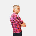 Ciclista con jersey de ciclismo Pas Normal Studios Essential en estampado rosa y negro, corte relajado y tejido técnico.
