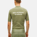Jersey de ciclismo verde oliva Pas Normal Studios Essential con ajuste relajado y bolsillos traseros, visto de espaldas.