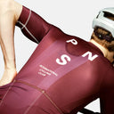Ciclista con maillot Pas Normal Studios Mechanism burdeos de corte aerodinámico y tejido técnico transpirable