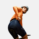 Ciclista mujer con maillot naranja y culotte azul marino de Pas Normal Studios en Velo Store Mx sobre bicicleta