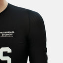 Detalle del hombro y logo de Velo Store Mx en el maillot de ciclismo negro Pas Normal Studios Mechanism Pro