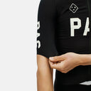 Maillot de ciclismo negro Pas Normal Studios Mechanism Pro con ajuste aerodinámico y detalles de marca en la manga.