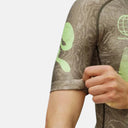 Maillot de ciclismo Pas Normal Studios Mechanism en color tierra con estampado topográfico y logo verde neón.