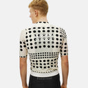 Ciclista de espaldas vistiendo el jersey Pas Normal Studios Essential en color Dot Bone con estampado de puntos negros.