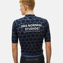 Ciclista vistiendo el jersey Pas Normal Studios Essential en color Dot Dark Navy con patrón de puntos y logo trasero.