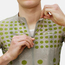 Ciclista vistiendo el jersey Pas Normal Studios Essential en color Dot Bone con cierre frontal y logo estampado