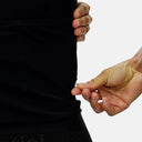 Detalle de la mano ajustando el tejido técnico negro del jersey de ciclismo Pas Normal Studios Essential para mujer